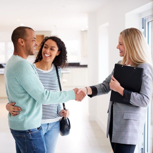 A happy homeowner couple shake hands with their underwriter after their mortgage application is approved