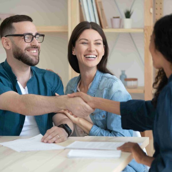 happy couple homeowners shaking hands with their underwriter after successfully completing the mortgage underwriting process